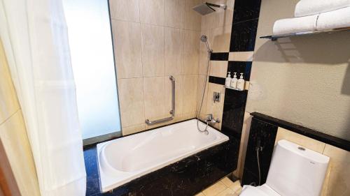 a bathroom with a bath tub and a toilet at Holiday Inn Cikarang Jababeka by IHG in Cikarang