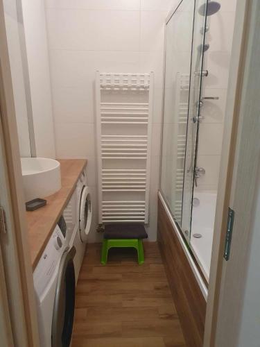 a small bathroom with a shower and a green stool at Szófia Wellness Apartman in Nagykanizsa