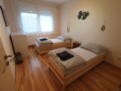 2 camas en una habitación con suelo de madera en Szófia Wellness Apartman, en Nagykanizsa