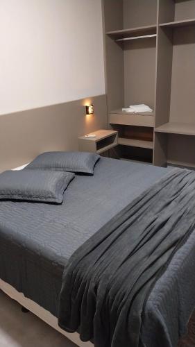 1 dormitorio con 1 cama grande con manta azul en Flat's Da Bia, en Cananéia