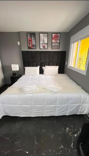 a large white bed in a bedroom with a window at Terraço Harmony Flats GRU in Guarulhos