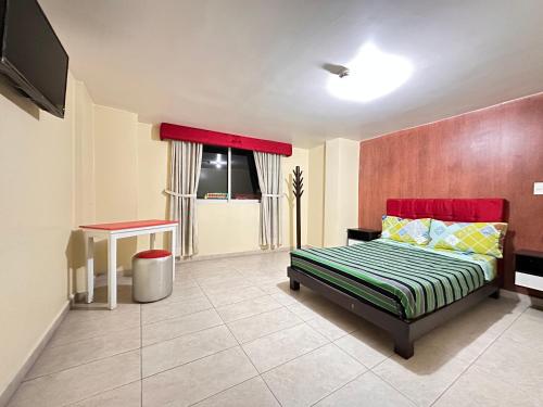 1 dormitorio con cama, mesa y TV en Hostal la perla del sur en Quito