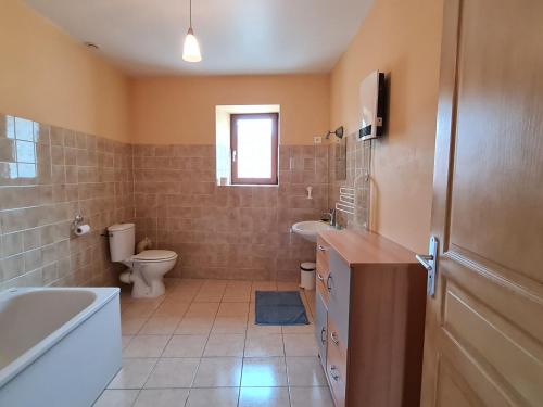a bathroom with a tub and a toilet and a sink at Maison spacieuse et confortable avec terrasse et jardin, idéale pour famille ou entreprise - FR-1-585-29 in Méligny-le-Grand