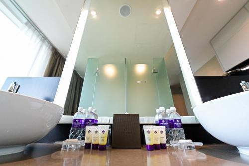 La salle de bains est pourvue d'un lavabo et d'un comptoir avec des bouteilles de savon. dans l'établissement Park Regis Singapore, à Singapour