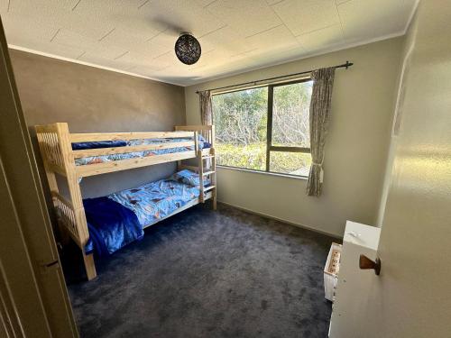 1 dormitorio con 2 literas y ventana en Streamside Family Friendly Oasis with Spa en Rotorua