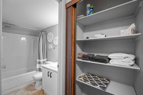 a bathroom with a shower toilet and towels on shelves at CHIC 2BR Near Keyano College Free Parking in Fort McMurray