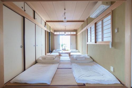 eine Reihe von Betten in einem Zimmer mit einem Tisch in der Unterkunft Hostel Ini kobe & Donut cafe in Kōbe