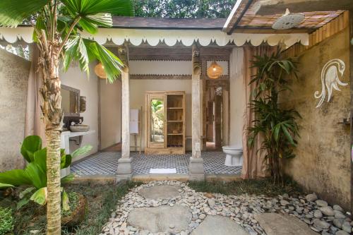 an entrance to a house with a palm tree at Sacred Beji by GenuineHost in Payangan