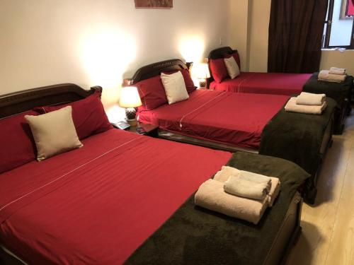 three beds in a room with red sheets and pillows at HOTEL en el CENTRO HISTORICO in Cuenca