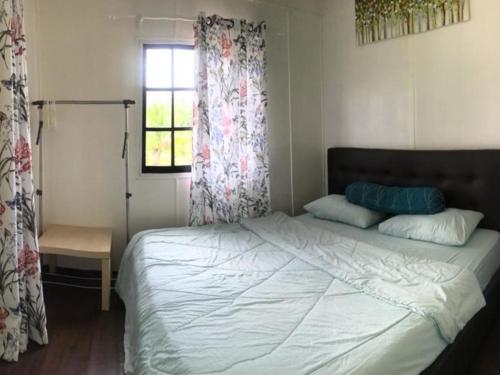 a bedroom with a bed and a window with curtains at Noungan Farm in Penampang