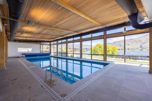 a large swimming pool in a building with windows at Marina Views - Luxury Apartment in Wanaka