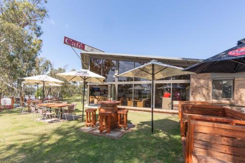 a restaurant with tables and umbrellas in the grass at Mannum Motel in Mannum
