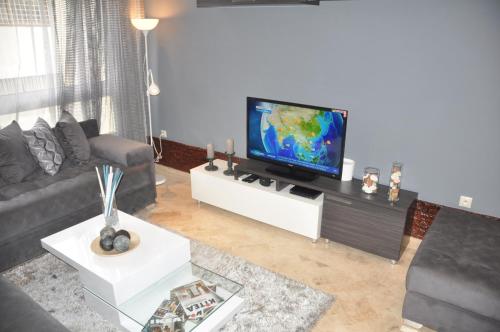 Val Fleuri Apartment with 2 Balconies, Casablanca في الدار البيضاء: غرفة معيشة مع تلفزيون بشاشة مسطحة على طاولة