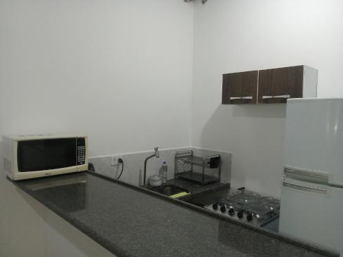 a kitchen with a counter with a microwave and a refrigerator at Casa mirante Bela Vista in Guarujá