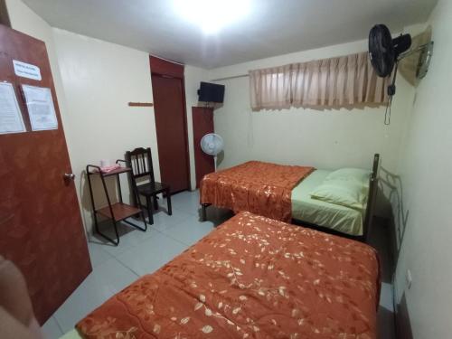 a small room with two beds and a chair at Hostal Cix - Chiclayo in Chiclayo