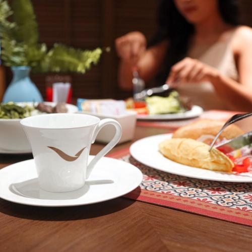 潘切Mövenpick Resort Phan Thiet的桌子上摆着几盘食物和一杯咖啡