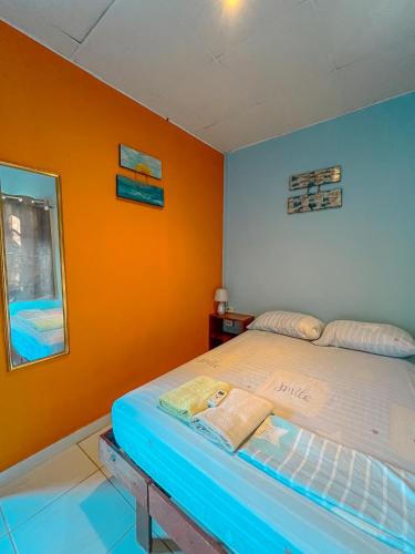 a bedroom with a bed with an orange wall at Surfari Bocas in Bocas del Toro