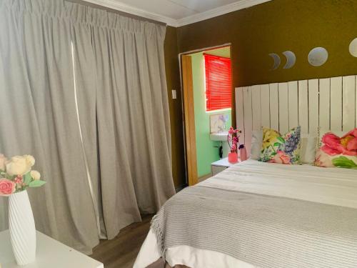 a bedroom with a large bed and a vase with flowers at SURVIVOR GUEST HOUSE-Giyani in Giyani