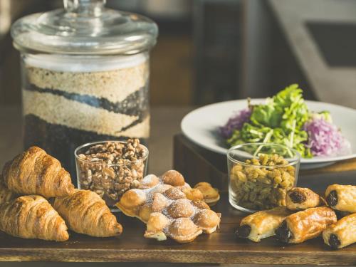 a table with bread and pastries and a plate of salad at HOTEL ANTEROOM NAHA in Naha