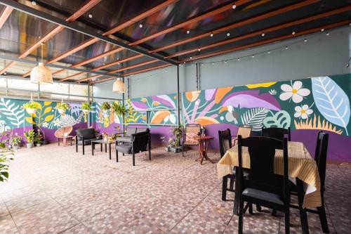 a room with tables and chairs and a colorful wall at Viva Guest House in San José