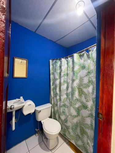 a bathroom with a toilet and a shower curtain at Hostal Los Chamos in San Juan del Sur