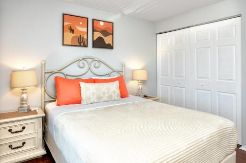 a bedroom with a white bed with orange pillows at Stylish Clearwater place. 3 Pools. Mins to Beaches in Clearwater