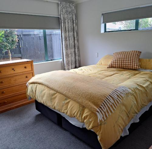 ein Schlafzimmer mit einem Bett mit einer Kommode und einem Fenster in der Unterkunft Hosts on the Coast - Rosberg Retreat in Mount Maunganui
