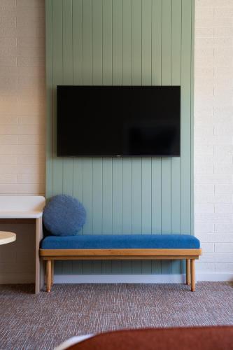 un banco azul con TV de pantalla plana en la pared en The Clovercrest Hotel Motel, en Modbury