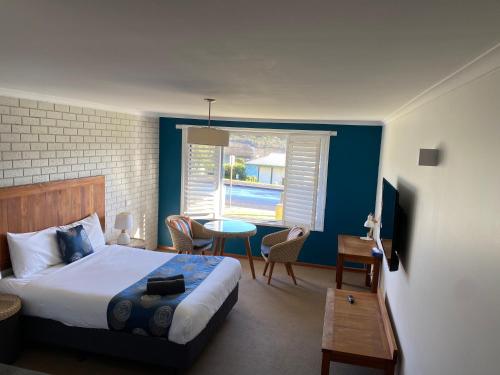 1 dormitorio con cama, mesa y ventana en Southern Ocean Motor Inn, en Port Campbell