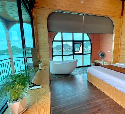 a bedroom with a tub and a bed and windows at Le Pont Bungalow Cat Ba in Cat Ba