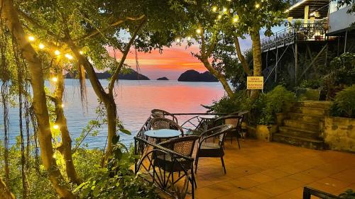 a patio with a table and chairs with a view of the water at Le Pont Bungalow Cat Ba in Cat Ba