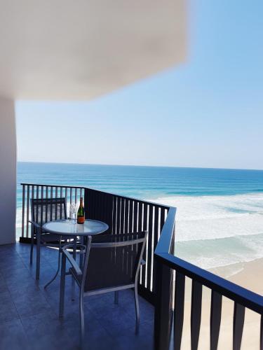 a table and chairs on a balcony with the beach at Golden Sands on the Beach - Absolute Beachfront Apartments in Gold Coast