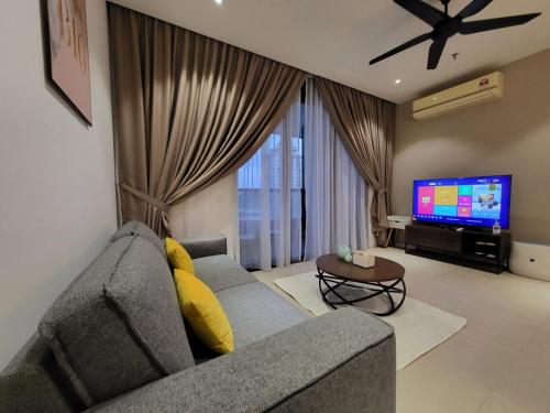 un salon avec un canapé gris et une télévision dans l'établissement Arcoris Mont Kiara, à Kuala Lumpur