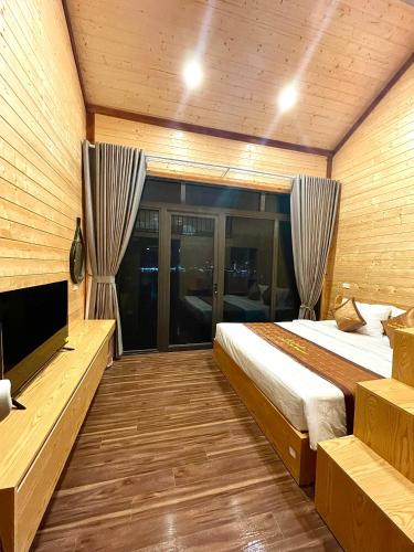 a bedroom with a bed and a flat screen tv at Le Pont Bungalow Cat Ba in Cat Ba