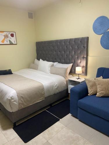 a bedroom with a large bed and a blue couch at Apartaestudio nuevo en Tunal in Bogotá