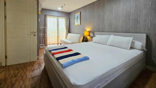 a bedroom with a large white bed and a chair at Quiet Low Level Lake View 3BRs Lippo Cikarang EJIP -Min Stay 3 Nights- in Bekasi