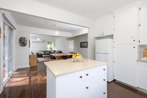 a kitchen with white cabinets and a table with a bowl of fruit at Serenity Halls Gap 2 Absolute NP Frontage in Halls Gap