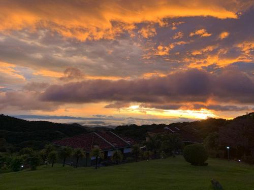 a sunset over a house in a field at Hotel Montaña Monteverde in Monteverde Costa Rica