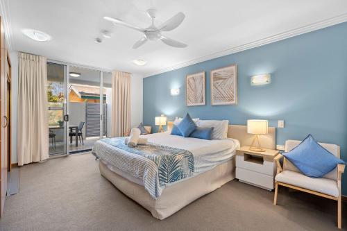クーラムビーチにあるUnit 30-31 12 Perry Streetの青い壁のベッドルーム1室、ベッド1台、椅子1脚が備わります。