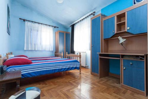 ein blaues Schlafzimmer mit einem Bett und einem Schreibtisch in der Unterkunft Apartment Ingrid in Pula