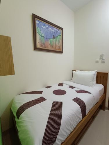 a bed in a room with a picture on the wall at The Cabin Hotel Sumberan in Yogyakarta