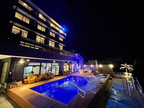 a swimming pool in front of a building at night at 【CLUB DEEP BLUE】西伊豆　知る人ぞ知る美しい入江が眺める貸別荘！最大44人宿泊可能！ in Numazu