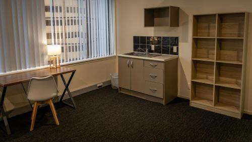 a room with a desk and a sink and a window at Choice Backpackers in Auckland