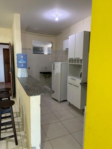 a small kitchen with white appliances and a counter at Residencial Edite Bulhões in Guaibim