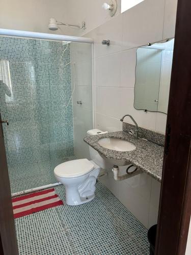 a bathroom with a toilet and a sink and a shower at Residencial Edite Bulhões in Guaibim