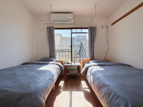 two beds in a room with a large window at Tabist A Mirai Oji in Tokyo