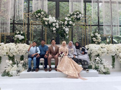 un grupo de personas sentadas en un banco en una boda en Wan Homestay en Sungai Petani