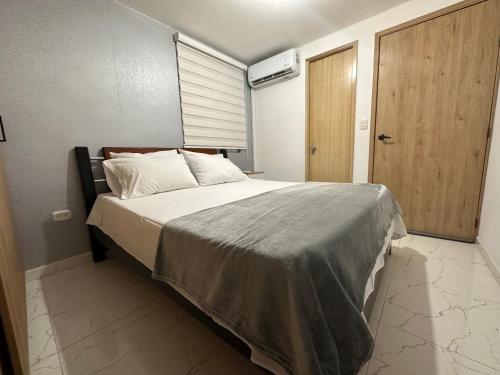 1 dormitorio con 1 cama grande y puerta de madera en Apartamento cerca al aeropuerto BILBAO, en Cúcuta