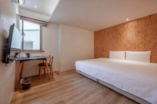 a hotel room with a bed and a desk at Light Hostel - Tainan in Tainan