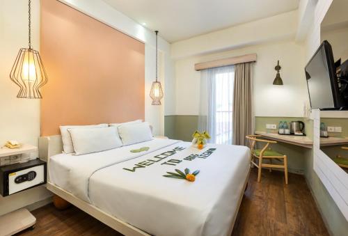 a bedroom with a large white bed with a desk at Boss Legian Hotel Powered by Archipelago in Legian